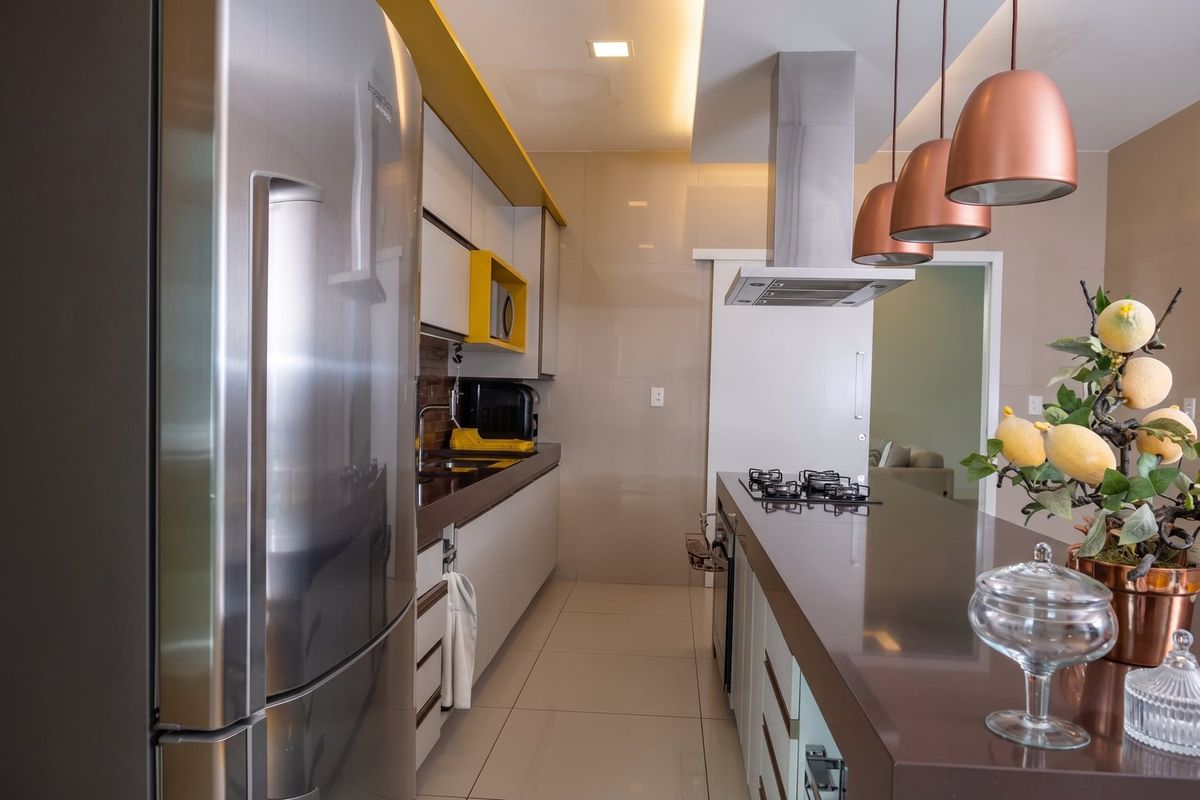 Cozinha com bancada marrom, coifa e pendentes em cobre