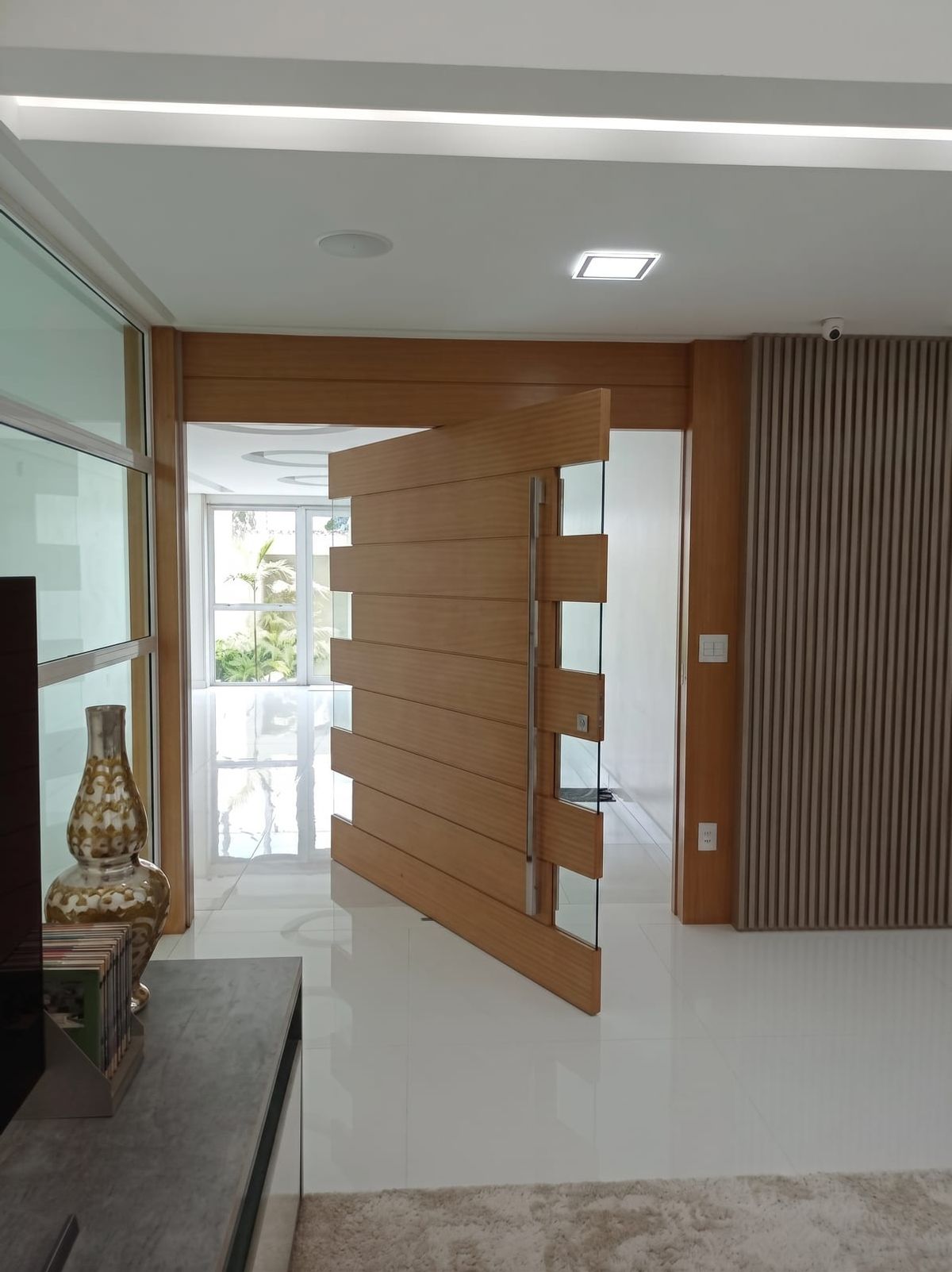 Hall de entrada com porta pivotante em madeira