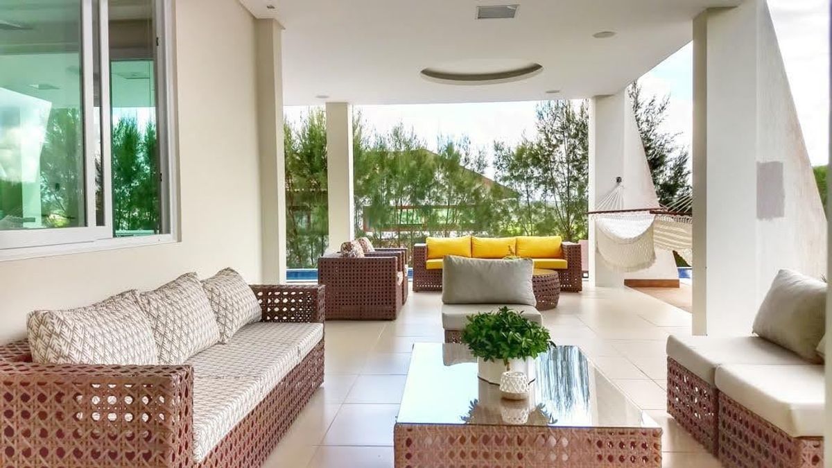 Varanda de estar com sofás de fibra, rede e vista para o jardim