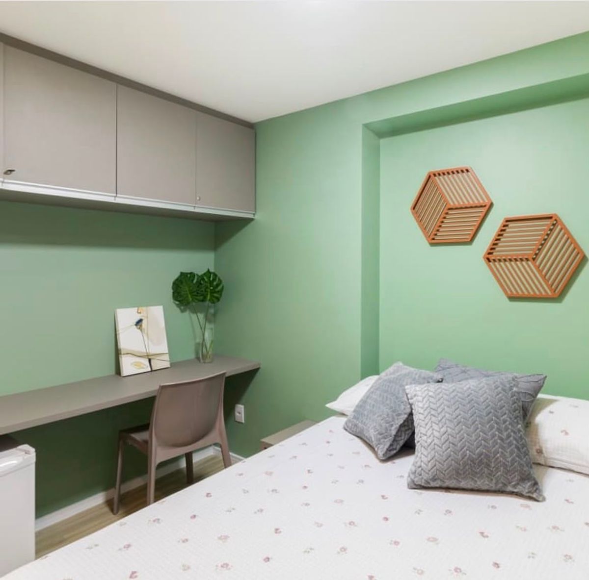 Dormitório com parede verde, escrivaninha planejada e nichos hexagonais
