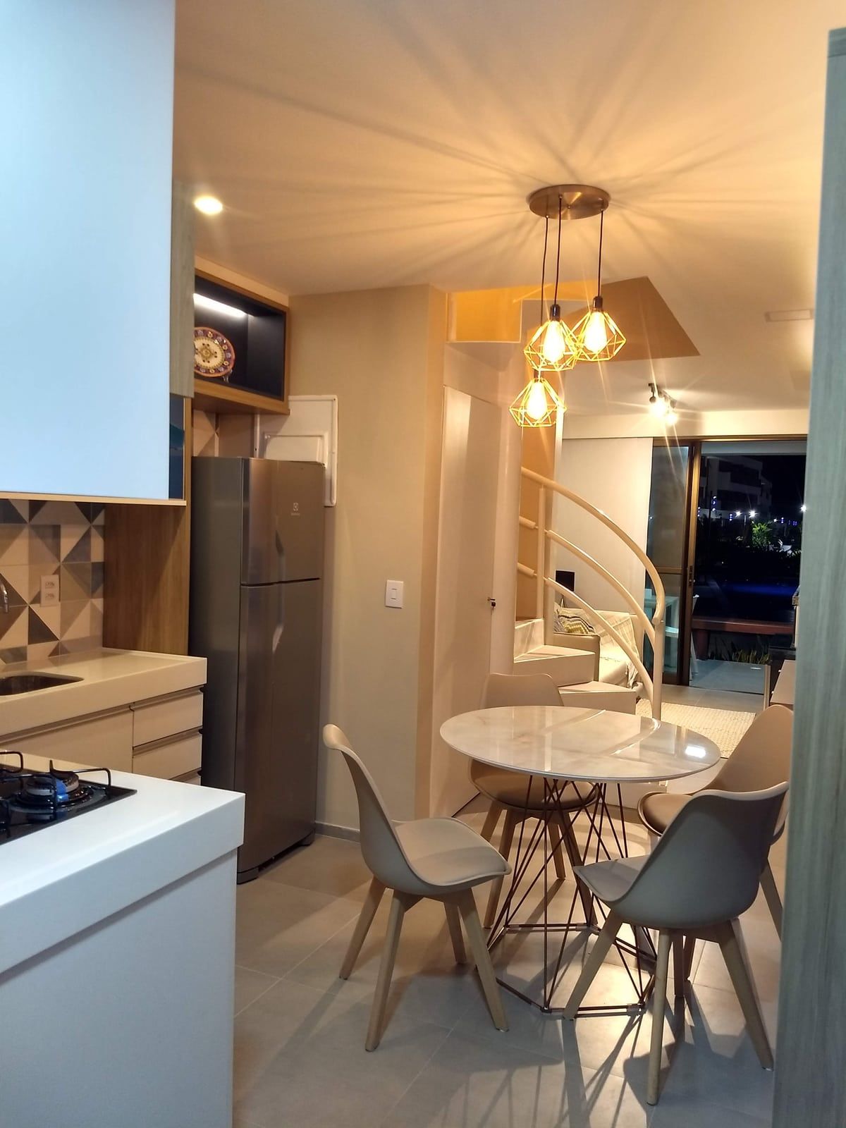 Cozinha e copa integradas, com mesa redonda de mármore e vista para a varanda