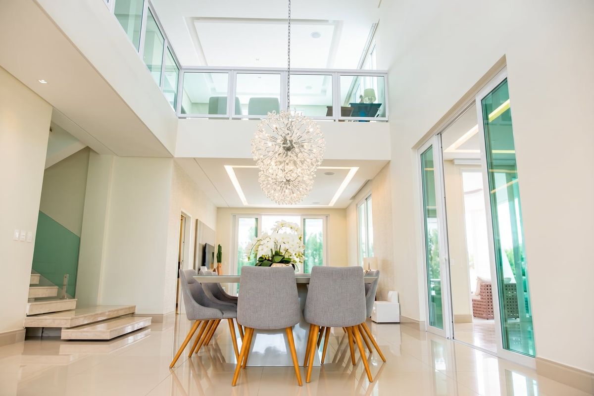 Sala de jantar em pé-direito duplo, com lustre de cristal e mezanino envidraçado