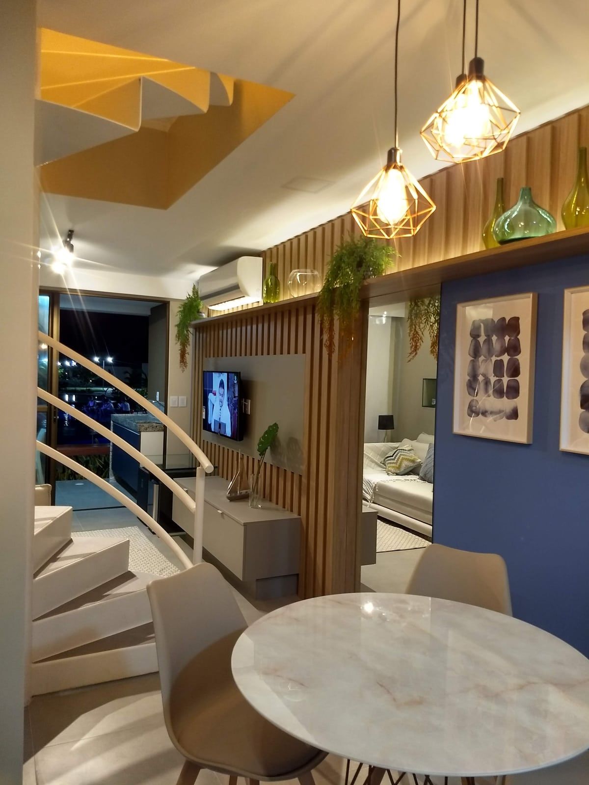 Living e jantar integrados, com escada caracol e parede azul decorada
