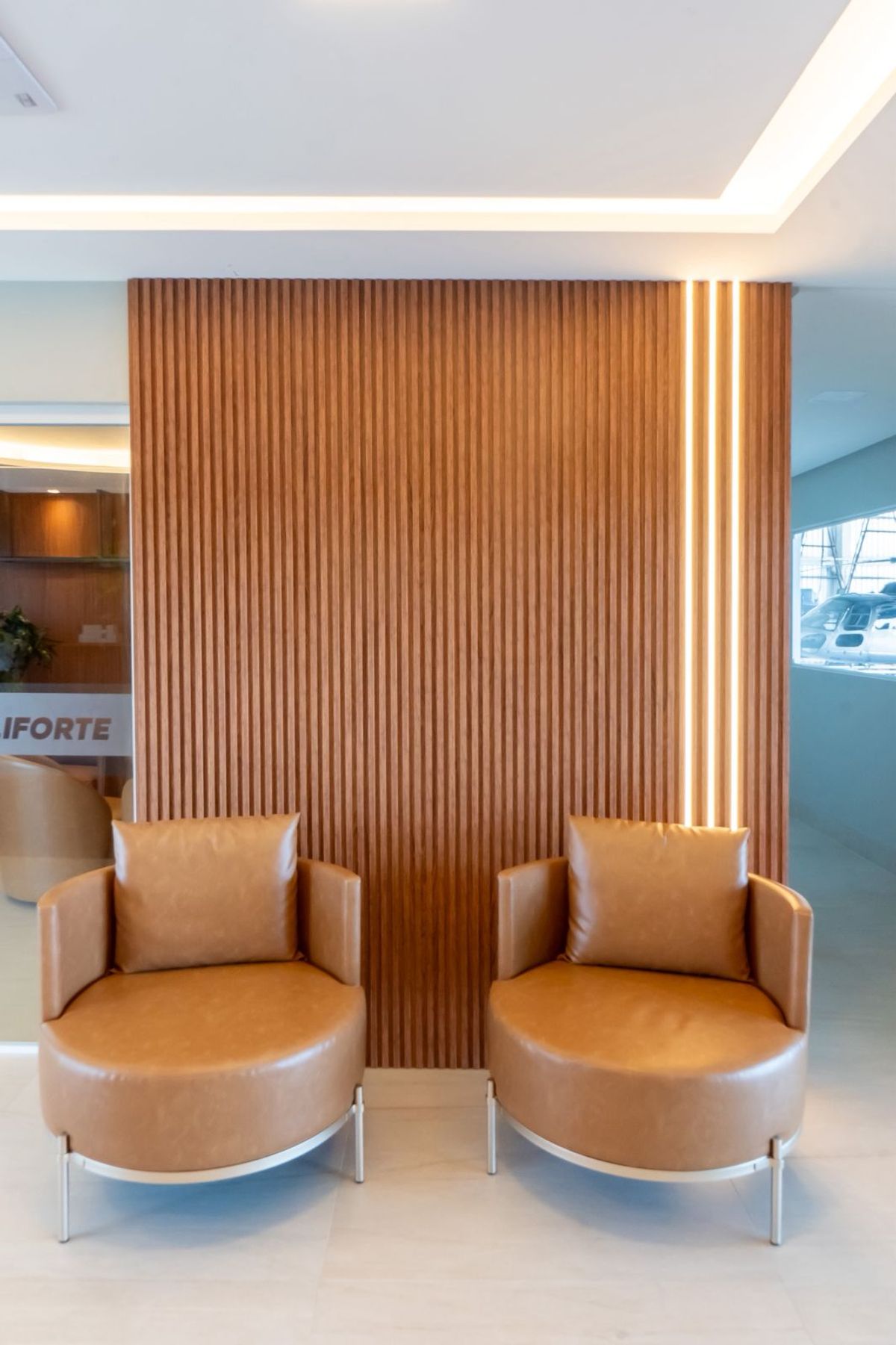 Sala de espera com poltronas e painel ripado iluminado