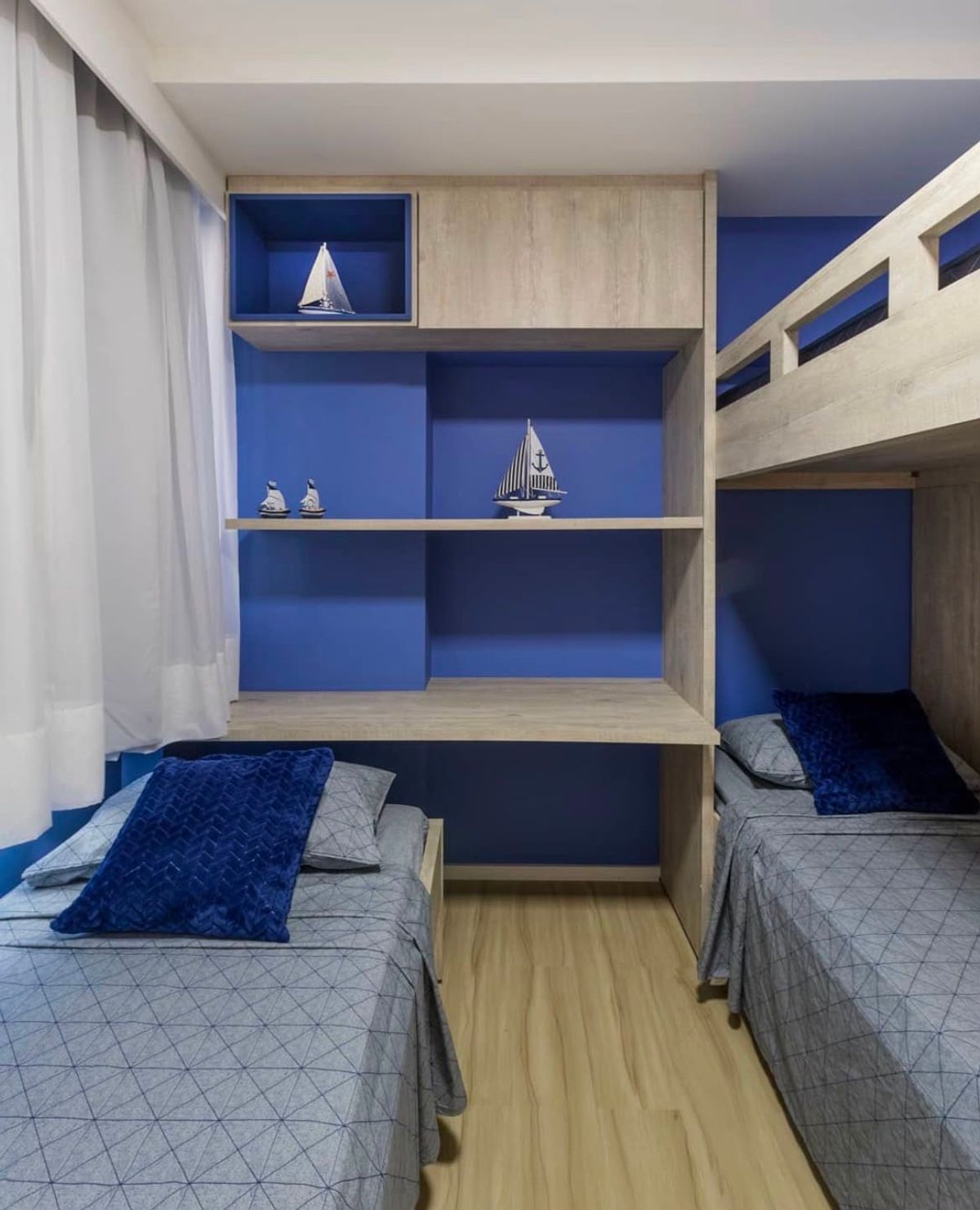 Quarto de tema náutico com beliche, marcenaria amadeirada e parede azul