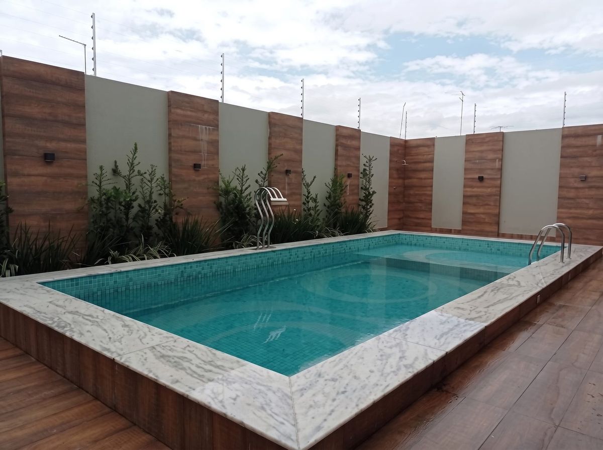 Área de piscina com deck de madeira e revestimento em mármore