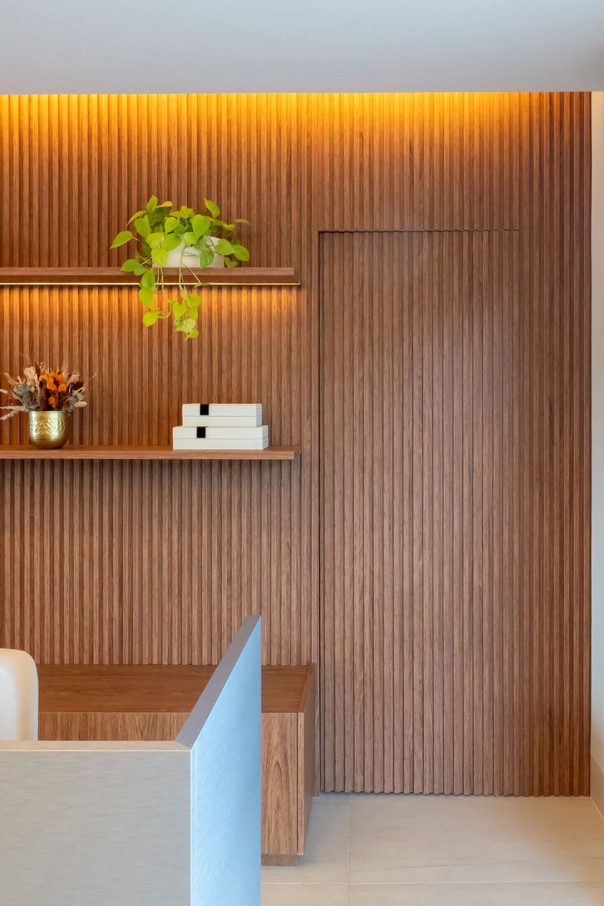 Painel ripado com porta camuflada e prateleiras decorativas