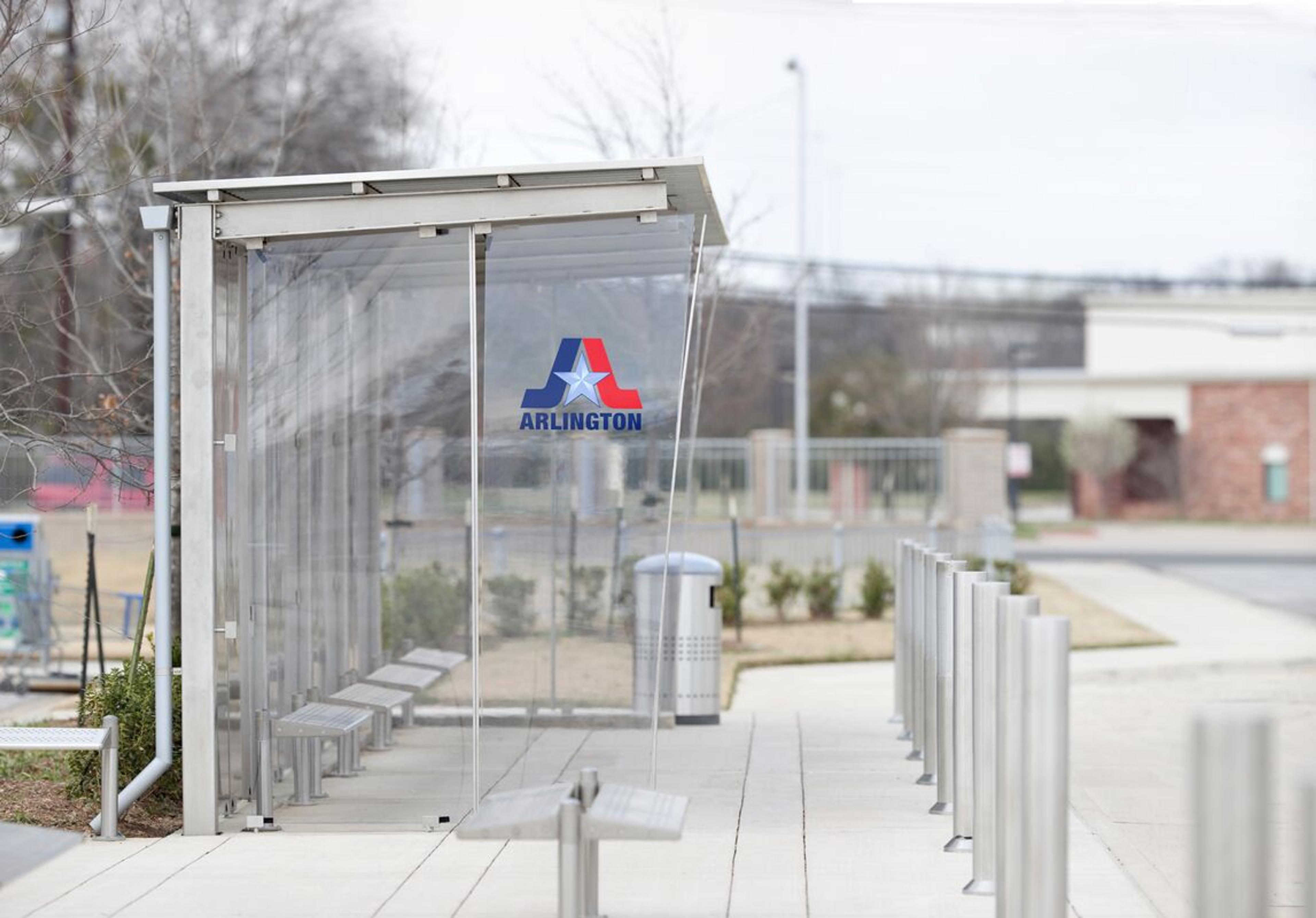 Custom transit shelter pairs architectural glass with a stainless steel frame • Custom stainless steel seating and receptacle • Cowboys Stadium • Dallas, Texas