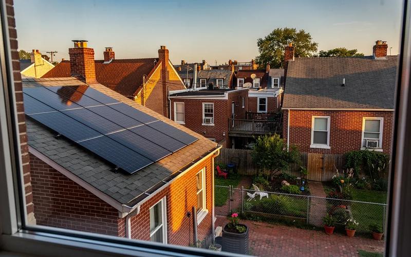 DC row house rooftop with conventional solar panels installed on the rear slope, viewed from a neighboring rooftop in Petworth