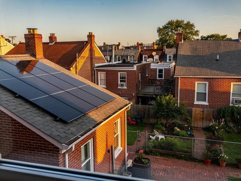DC row house rooftop with conventional solar panels installed on the rear slope, viewed from a neighboring rooftop in Petworth