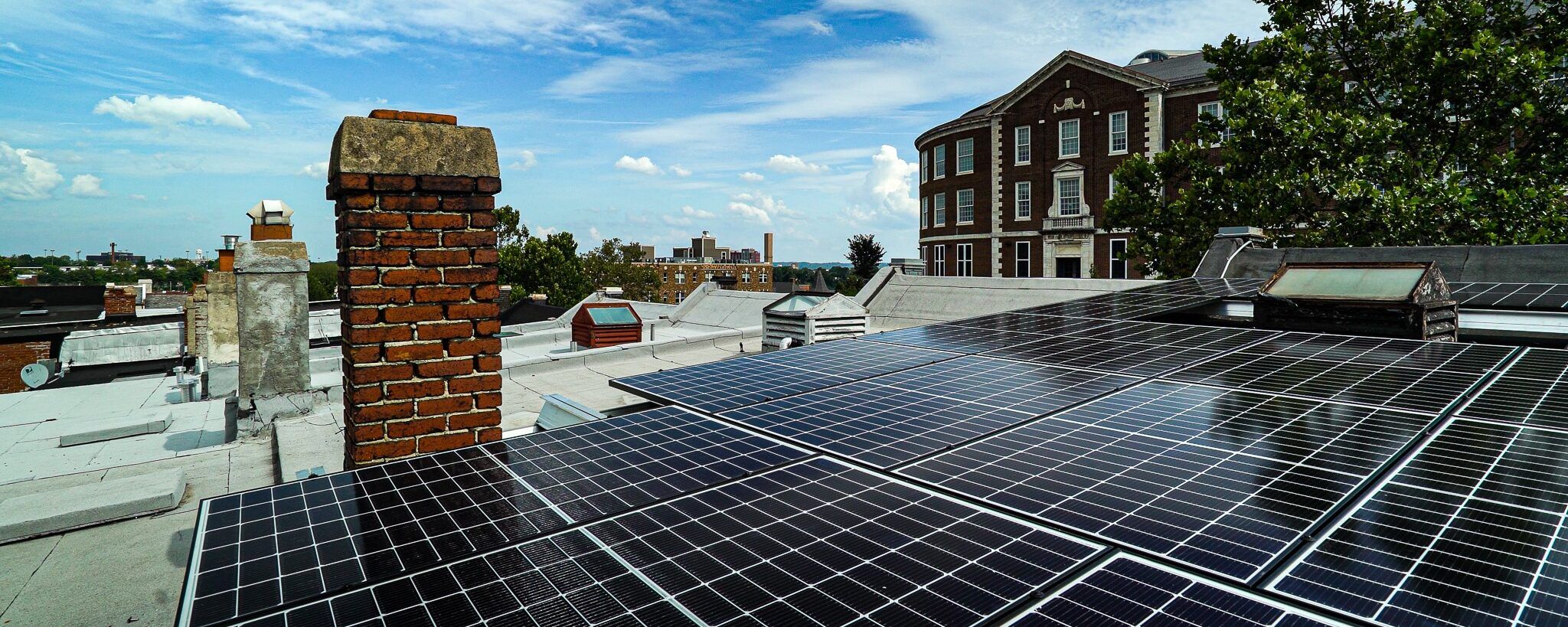 Solar panels on rooftop with buildings.