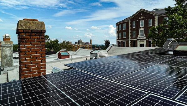 Solar panels on rooftop with buildings.