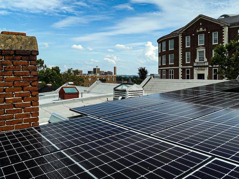 Solar panels on rooftop with buildings.