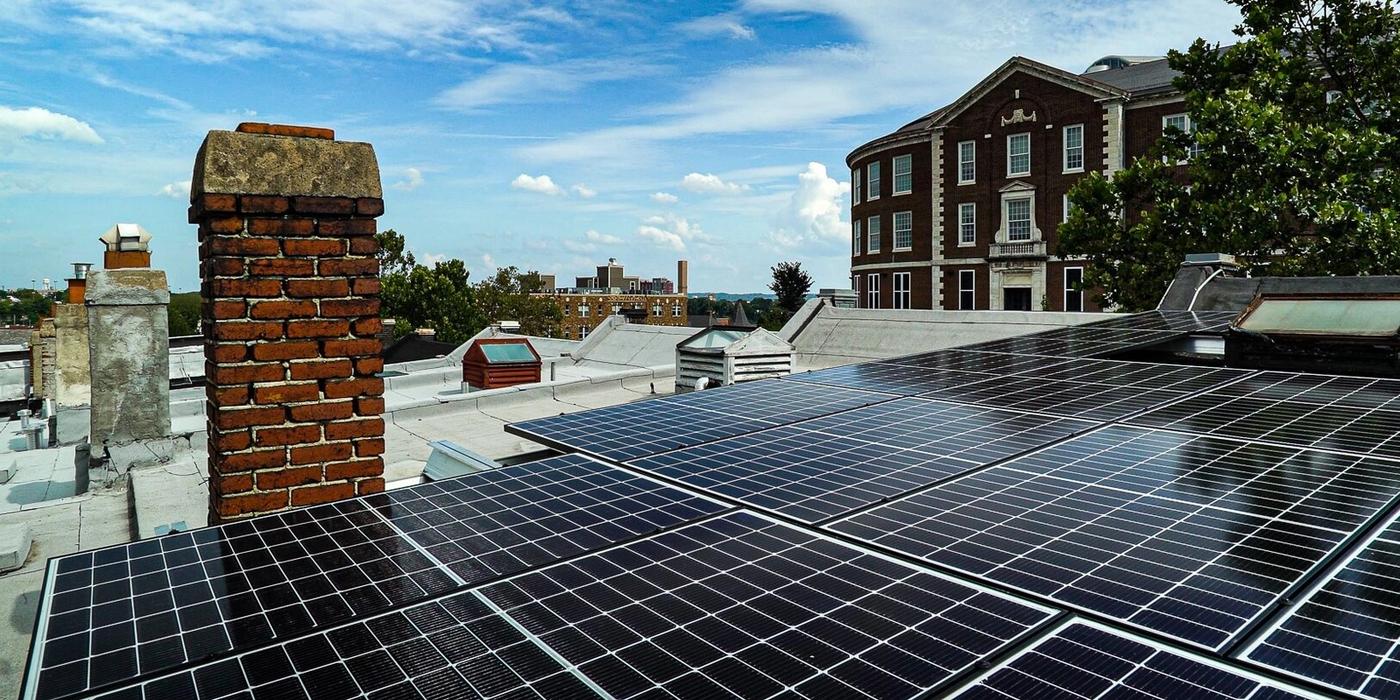Solar panels on rooftop with buildings.