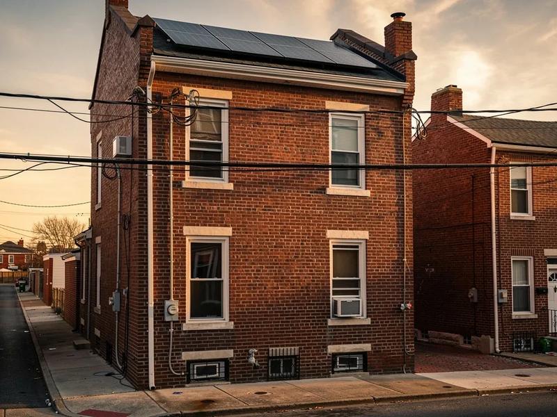 Solar panels on a DC row house roof with Pepco utility lines visible in the background, representing energy companies near me in Washington DC