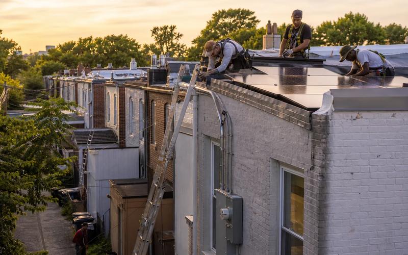 DC solar installers working on a rowhouse rooftop array in Washington, DC with service and monitoring focus