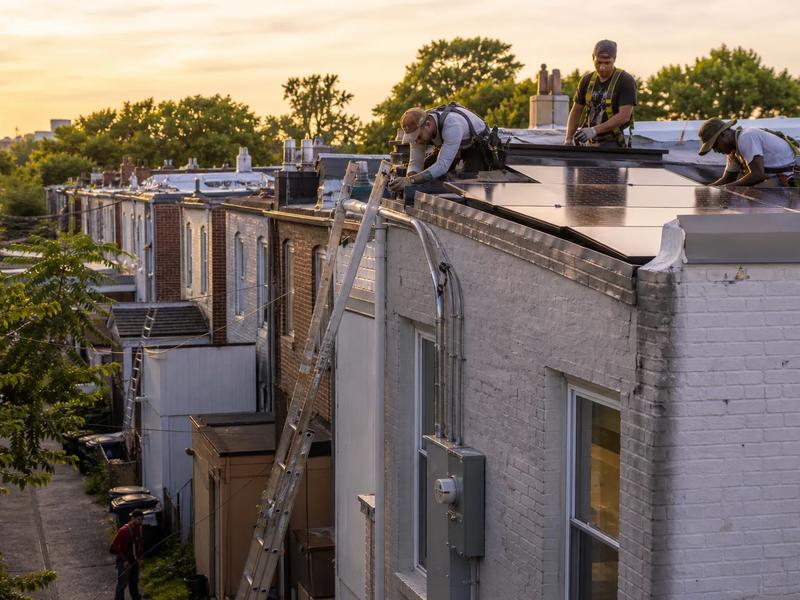 DC solar installers working on a rowhouse rooftop array in Washington, DC with service and monitoring focus