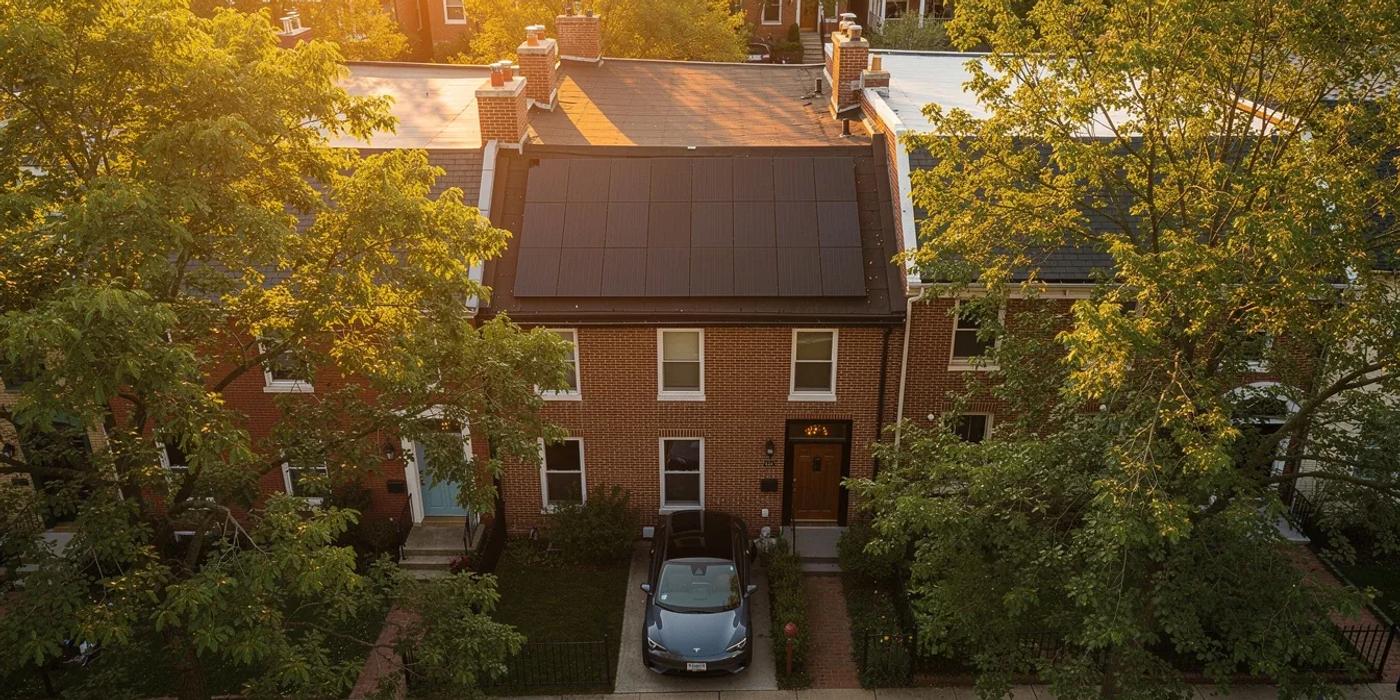 Solar panels on a DC row house roof with an electric vehicle parked in the driveway below
