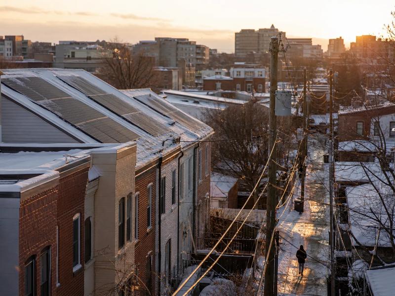 Winter in Washington DC with rowhouse rooftops and solar panels visible after light snowfall, illustrating solar panels working in winter