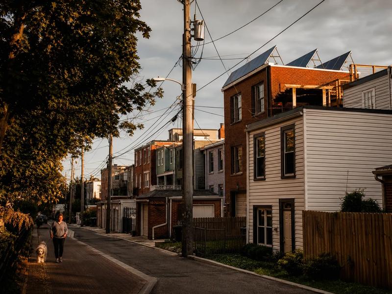 Washington, DC rowhouse block with rooftop solar panels visible, illustrating the shift from Tesla solar tiles to conventional panels