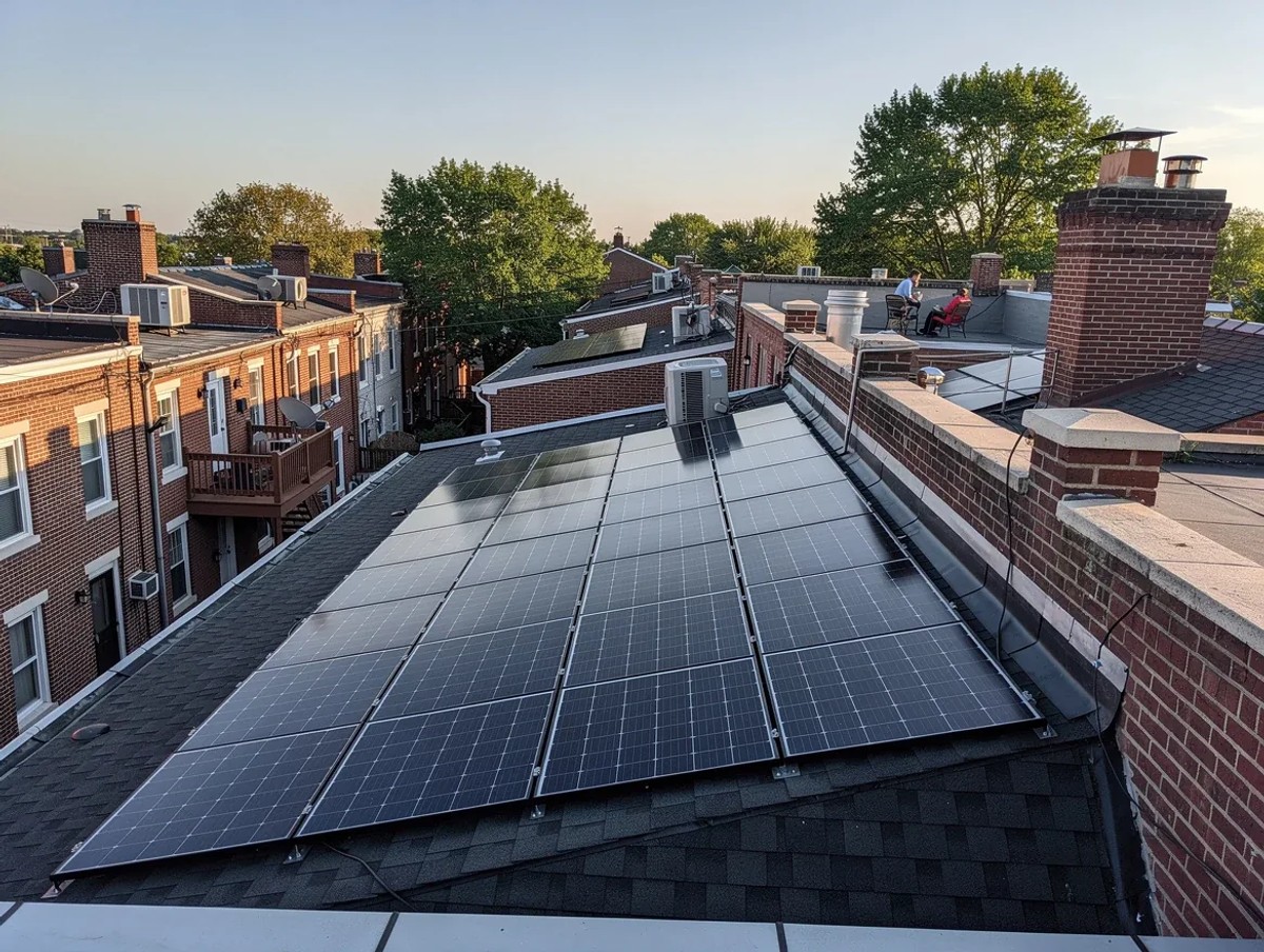 A rear rooftop view of a DC rowhouse with solar panels installed on the back slope, not visible from the street, urban DC neighborhood context, clear sky, photorealistic