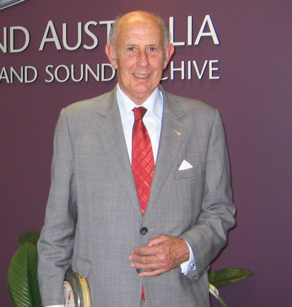 An elderly man in a suit and tie smiling