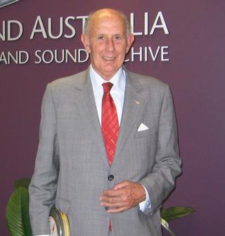 An elderly man in a suit and tie smiling