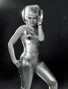 Woman in a gold jumpsuit with a fish bowl on her head as a helmet