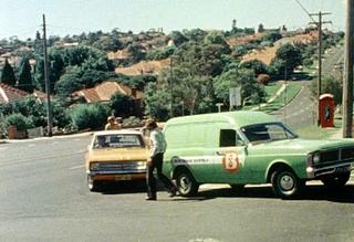 A green panel van and a yellow car involved in a traffic accident on a corner.