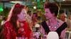 A scene from Muriel's Wedding with Toni Collette and Rachel Griffiths seated and looking directly at each other. They are both dressed up for a night out.