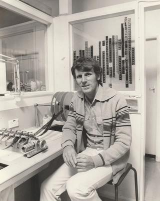 Portrait of Roger Cowland seated in a film splicing lab