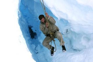 A man hanging from a rope on an icy mountain