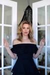 Actress Laura Gordon in a black dress standing between two open French doors