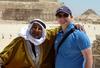 Two men standing in an archaeological site in a desert landscape and smiling.