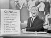 Still television image of Graham Kennedy holding an advertisement for Glo-Weave.