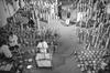 A black and white image of a room filled with hundreds of film canisters and mean in lab coats inspecting them.