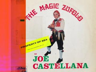A man in Sicilian folk costume playing a wooden flute. Text reads, The Magic Zufolo of Joe Castellana