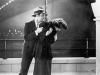A man clutching a woman on a footpath under a bridge in a scene from the 1938 movie Broken Melody.