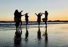Five First Nations dancers on a beach.