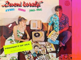 A young man sits among his music collection while his annoyed girlfriend looks at him