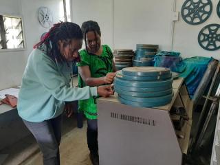 Two archivists inspecting a pile of film cans in the National Film Institute of Papua New Guinea.