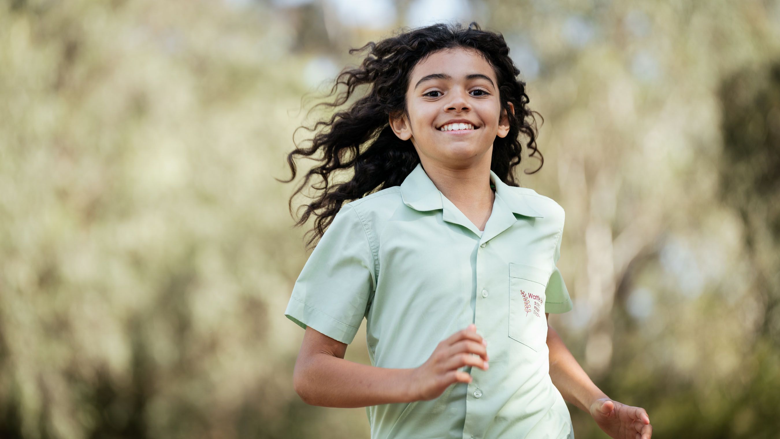 A young smiling girl runs toward the camera. 