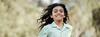 A young smiling girl runs toward the camera.