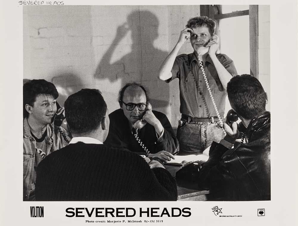 Promotional image for the band Severed Heads showing all the band members talking on telephones.