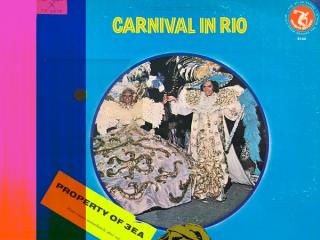 Blue record cover with central image of a man and woman dressed in outrageous carnival costumes