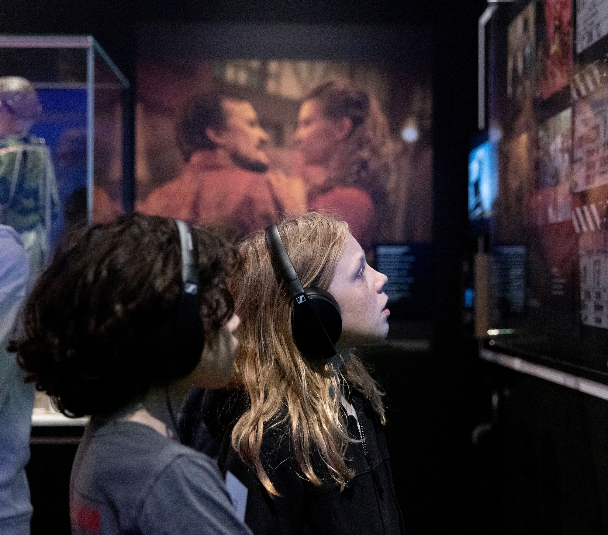 Two children wearing headphones gaze at an installation at the NFSA.