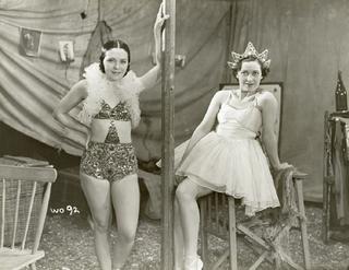 Two women is circus-type costumes inside a tent