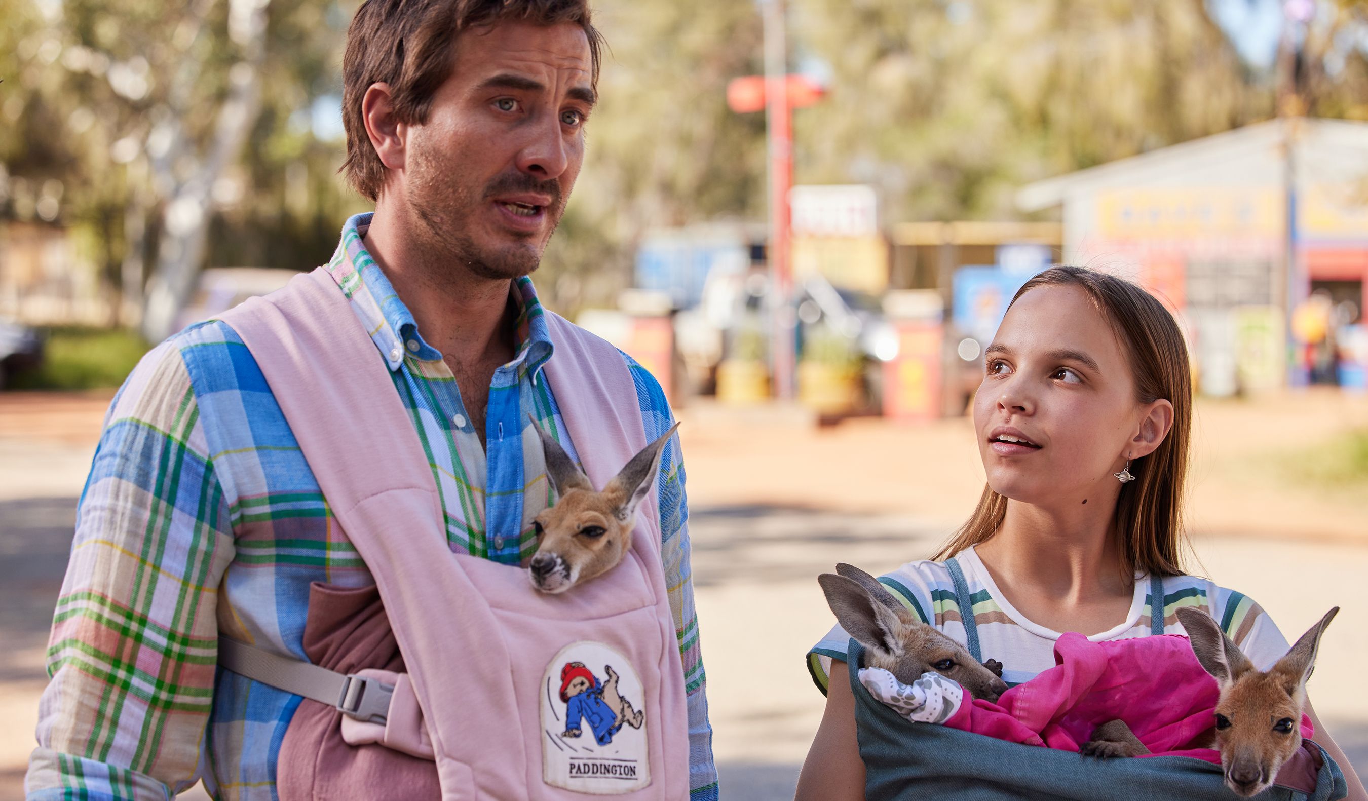 A man with a joey in a baby carrier stands next to a woman.