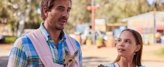 A man with a joey in a baby carrier stands next to a woman.