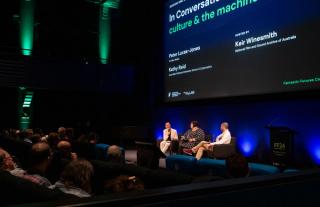 Peter-Lucas Jones, Kathy Reid and Keir Winesmith presenting a panel on a stage